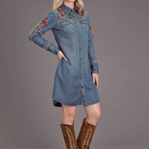 A woman in boots and jeans standing with her hands on the hips.